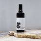 Black spray bottle with a white label on a wooden surface against a gray background