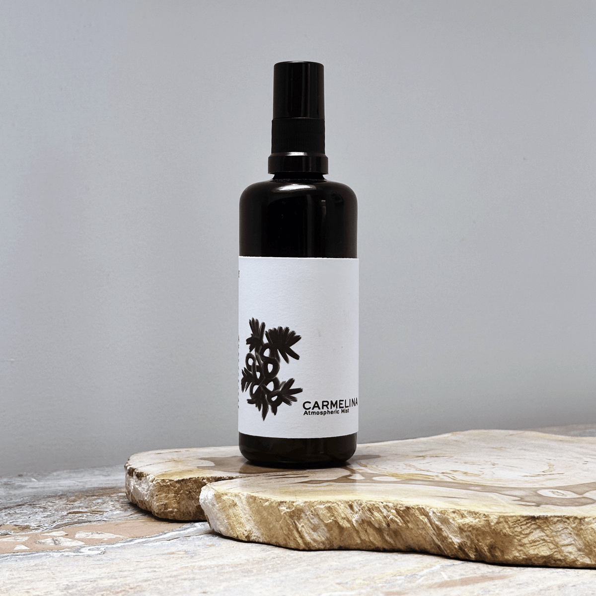 Black spray bottle with a white label on a wooden surface against a gray background