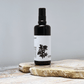 Black spray bottle with a white label on a wooden surface