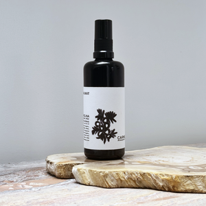 Black spray bottle with a white label on a wooden surface