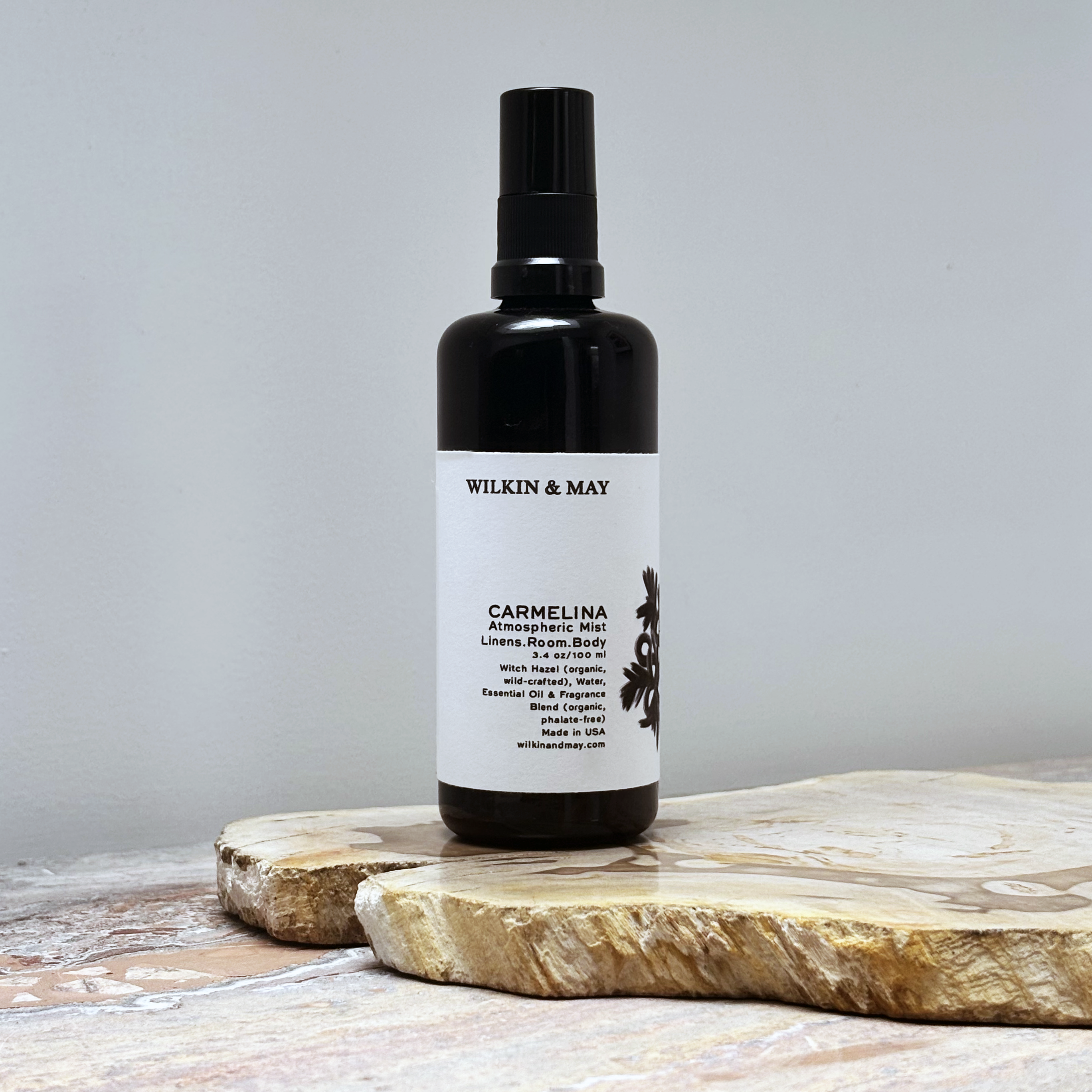 Black spray bottle with a white label on a wooden surface against a gray background