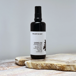 Black spray bottle with a white label on a wooden surface against a gray background