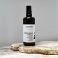 Black spray bottle with white label against a grey background