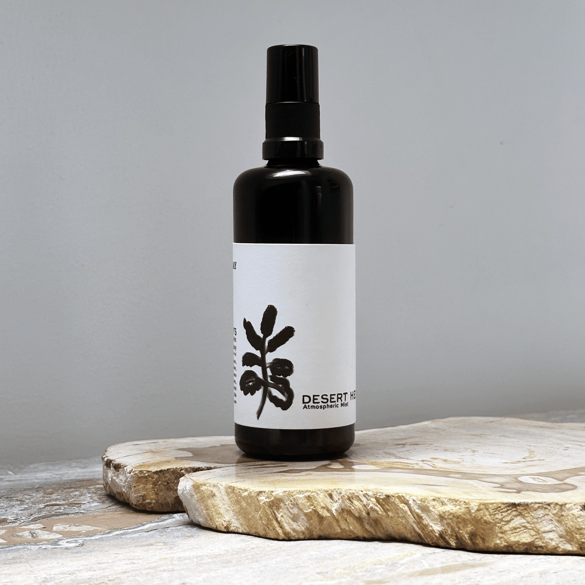 Black spray bottle with white label against a gray background