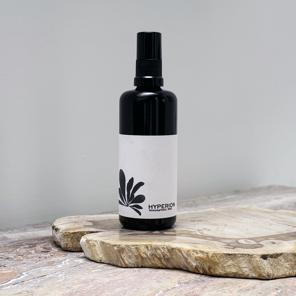 Black spray bottle with a white label featuring a logo on a wooden surface.