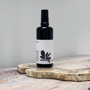 Black spray bottle with a white label on a wooden surface