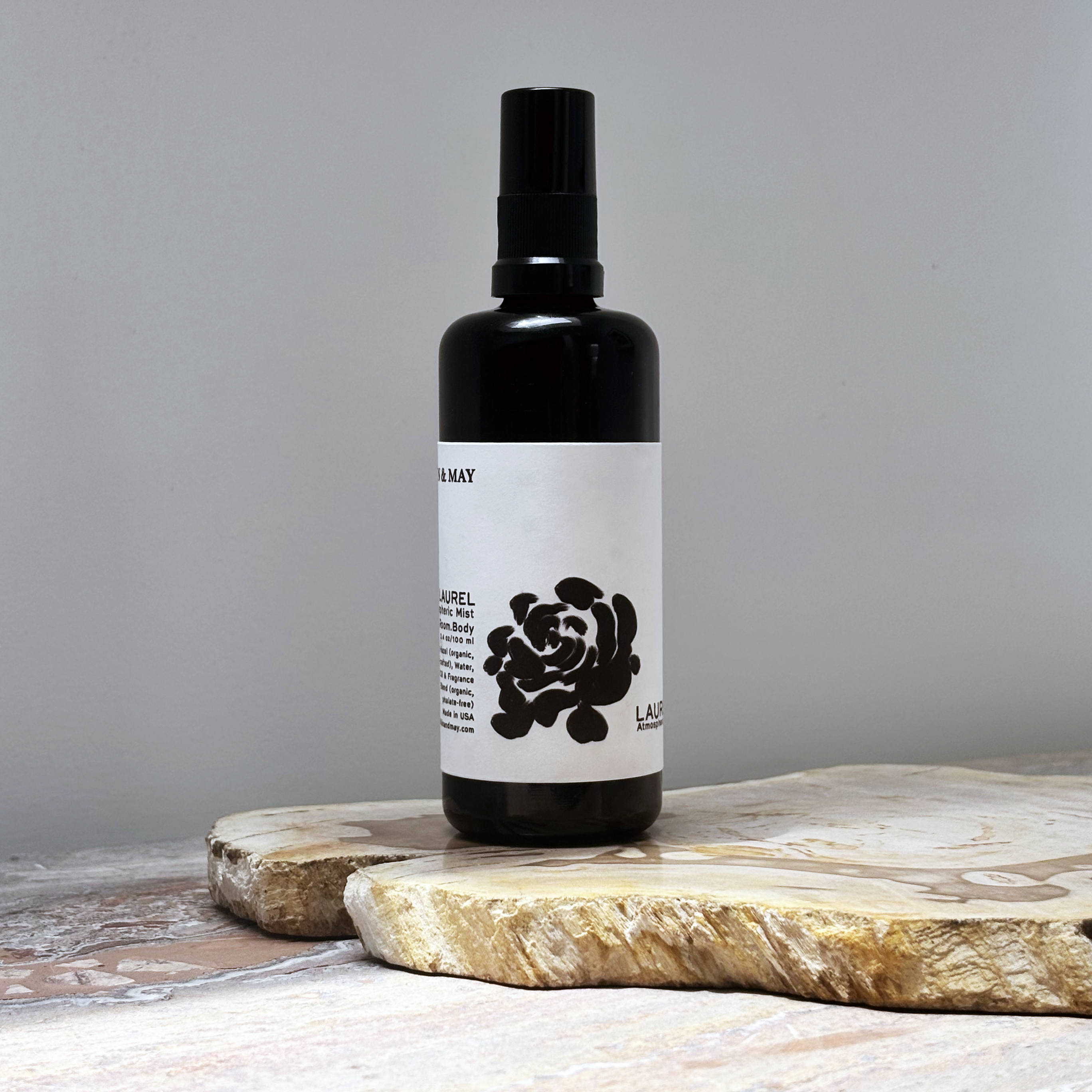 Black spray bottle with a white label featuring a black rose design on a wooden surface.