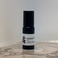 Black perfume bottle with a white label on a marble surface