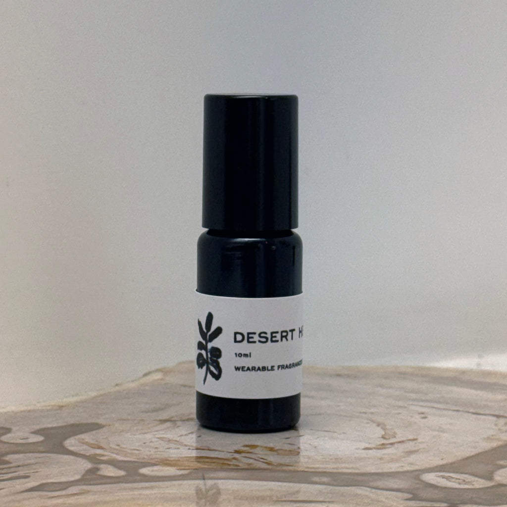 Black perfume bottle with a white label on a marble surface