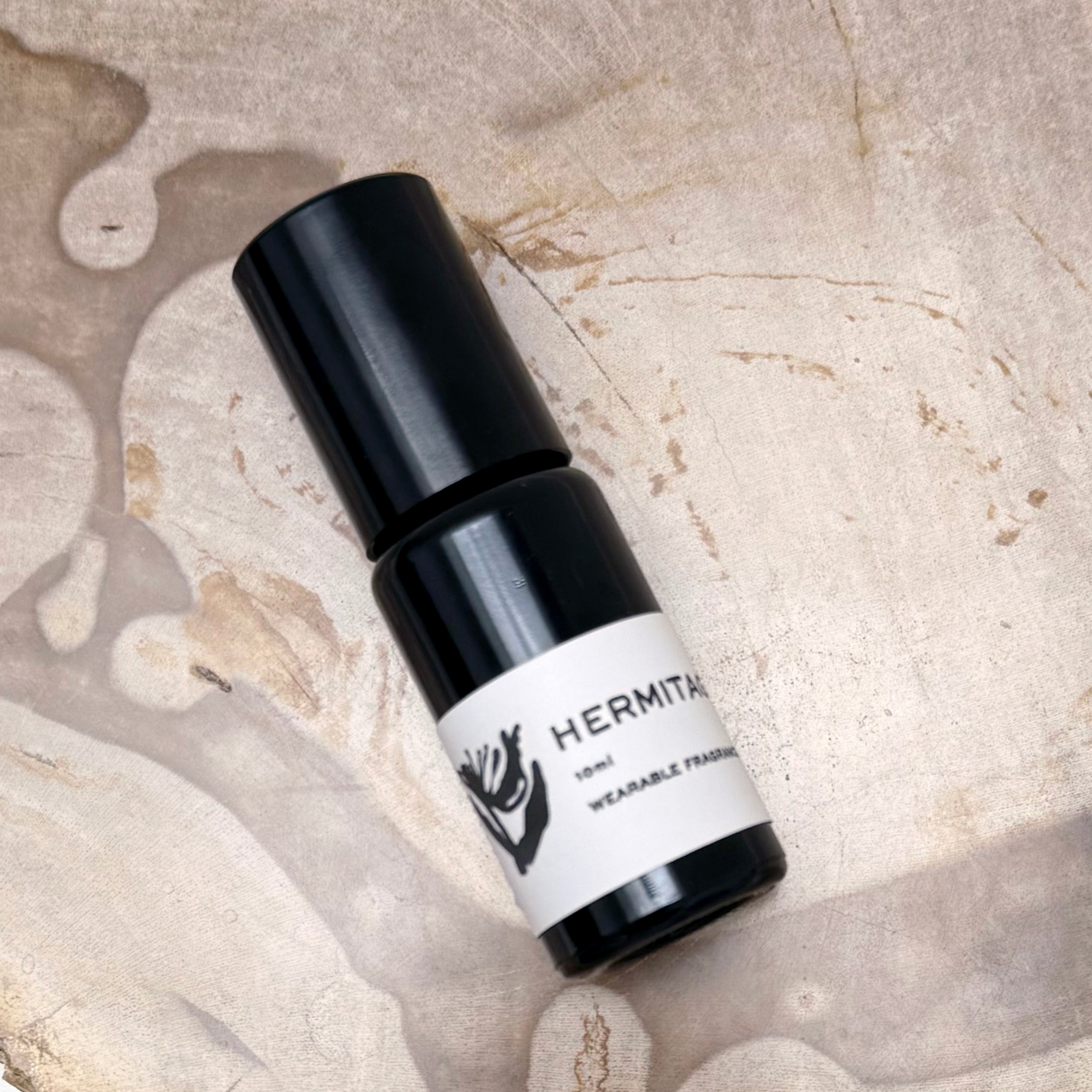 Black and white bottle labeled 'Hermitage' on a textured beige background