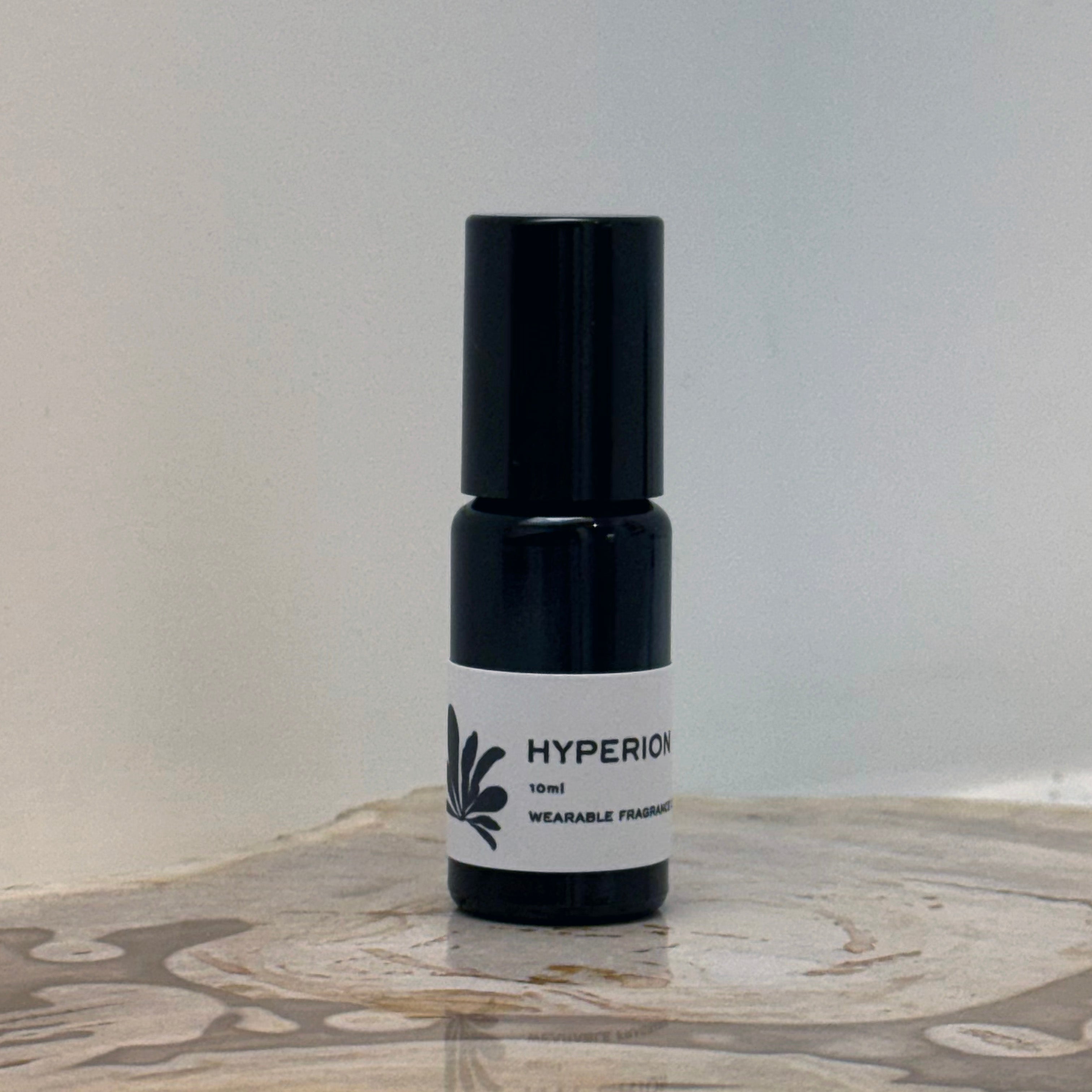 Small black and white bottle labeled 'HYPERION' on a marble surface with a light gray background