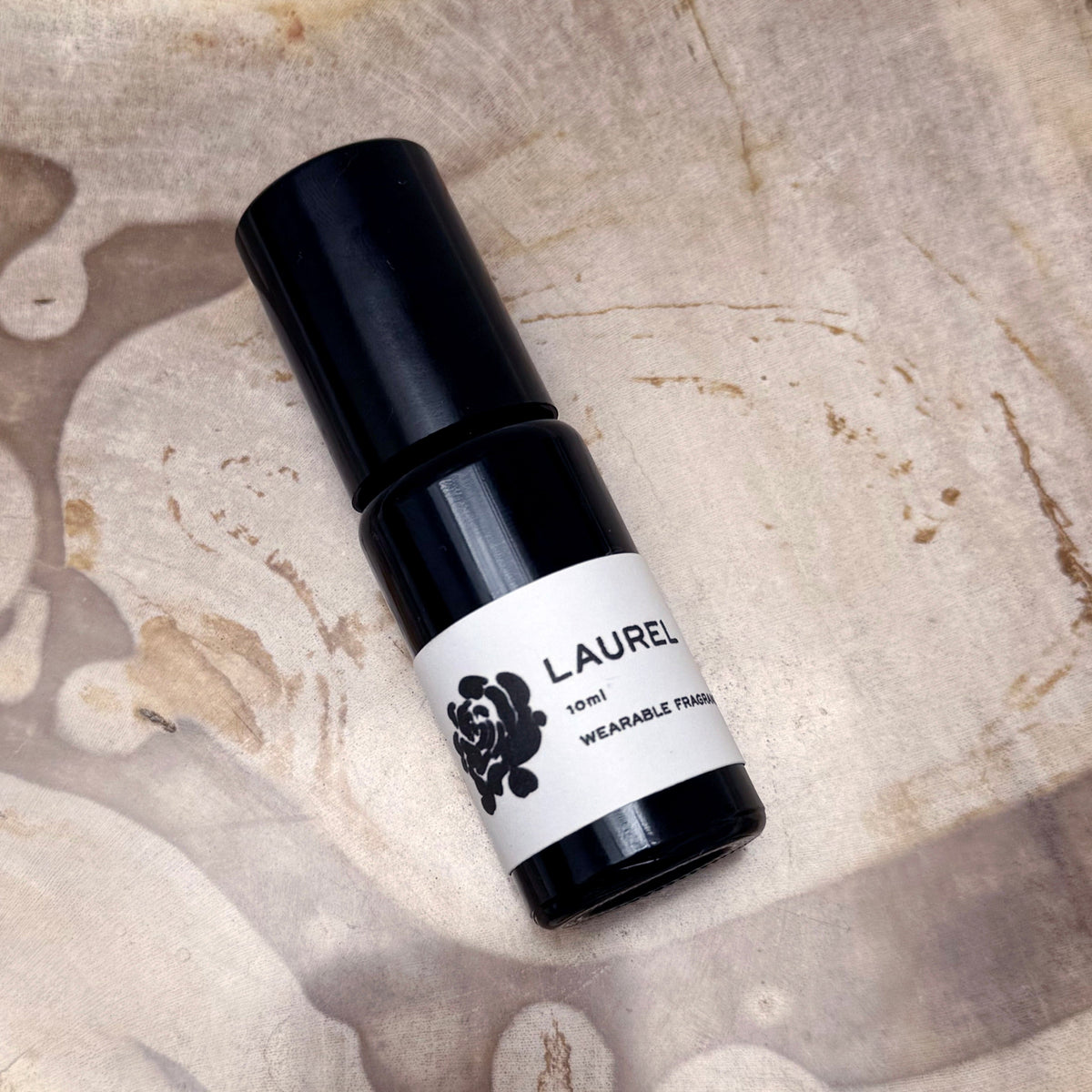 Black and white bottle labeled 'Laurel' on a textured beige background
