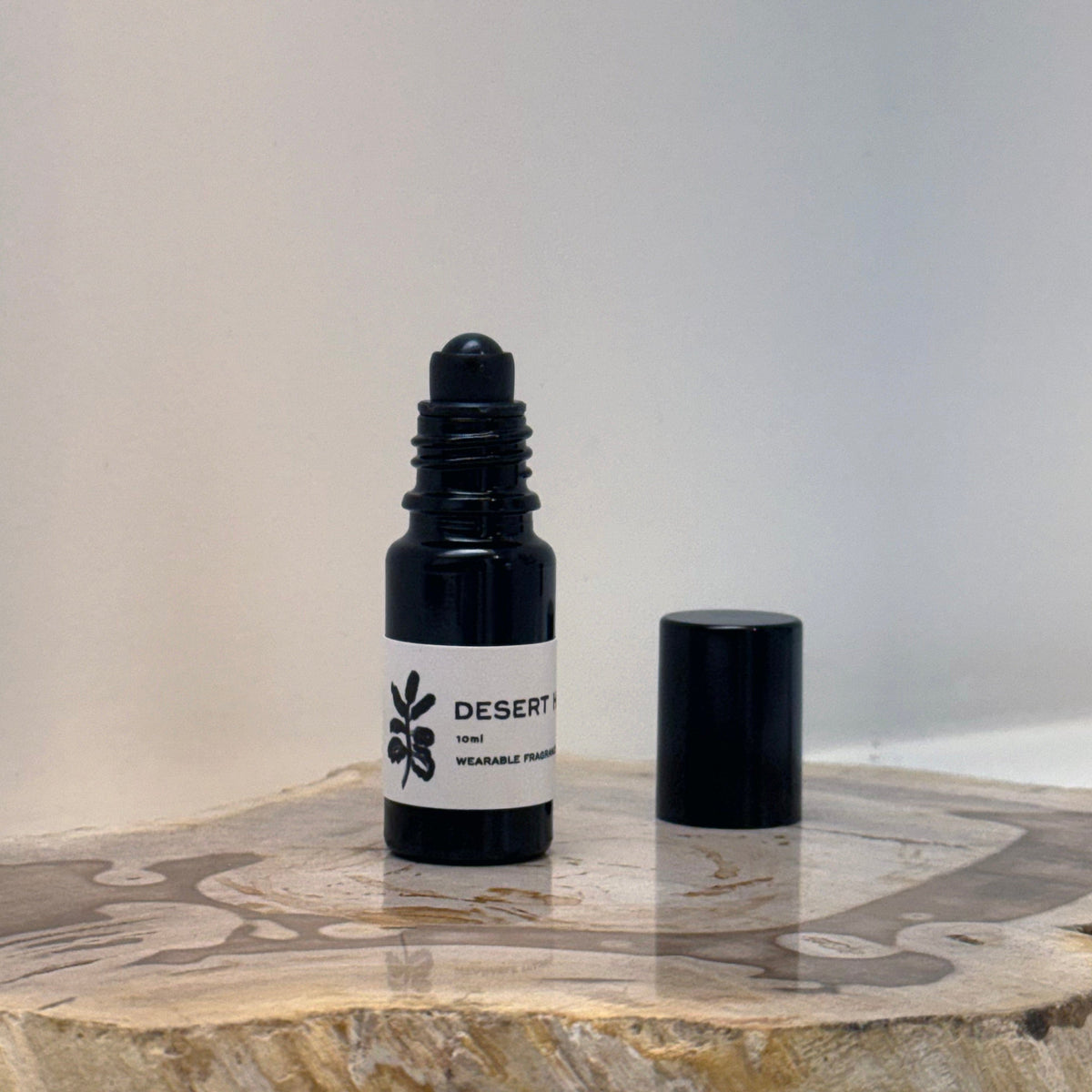 opened Black Roller bottle with white label sitting beside lid on wood surface
