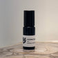 Black and white bottle of Hermitage perfume on a wooden surface with a neutral background