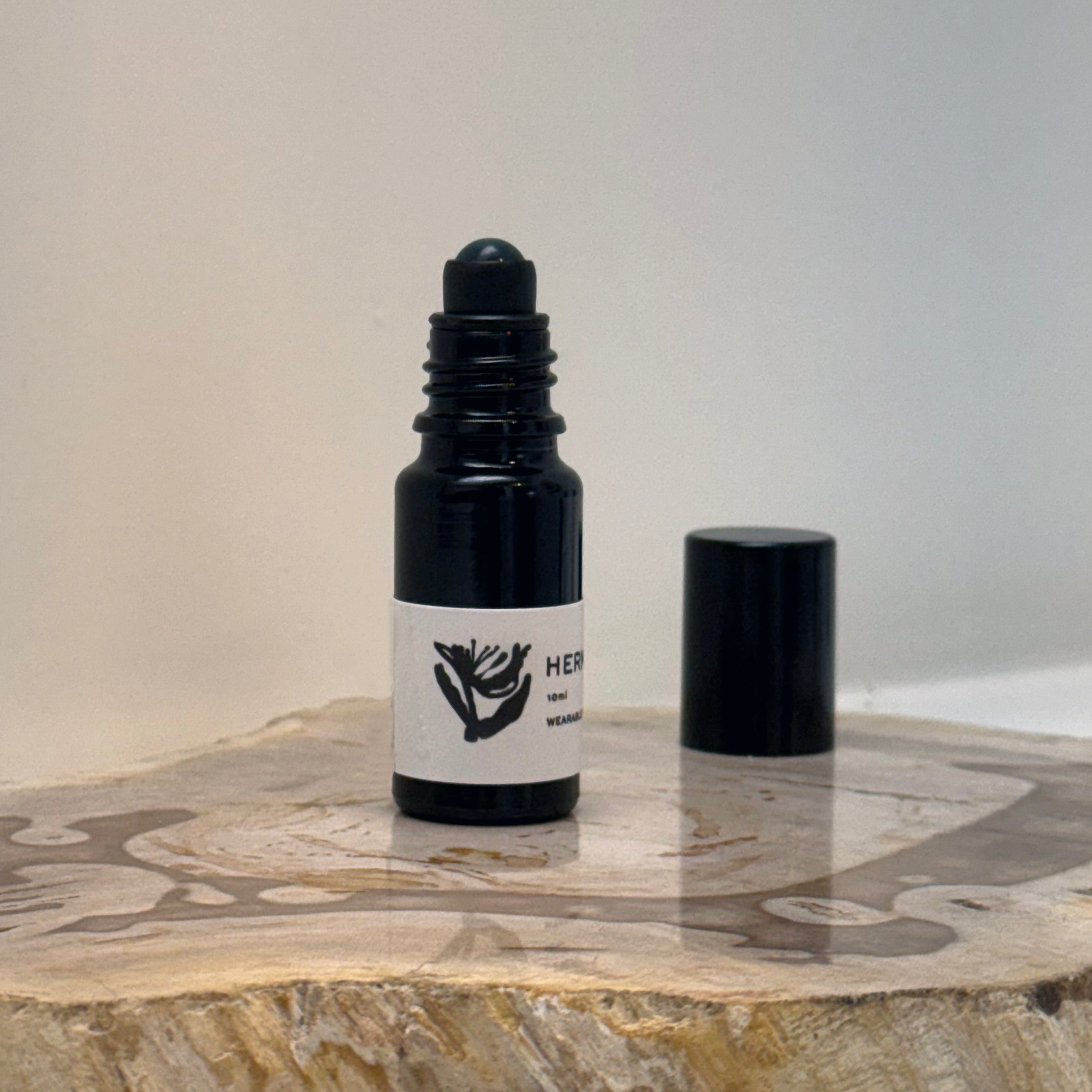 black opened bottle of Hermitage fragrance oil roller on a wooden surface