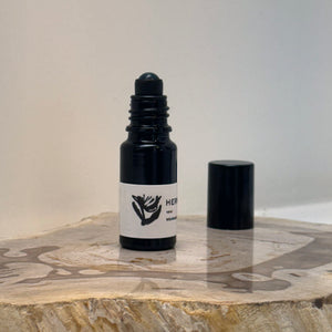 black opened bottle of Hermitage fragrance oil roller on a wooden surface
