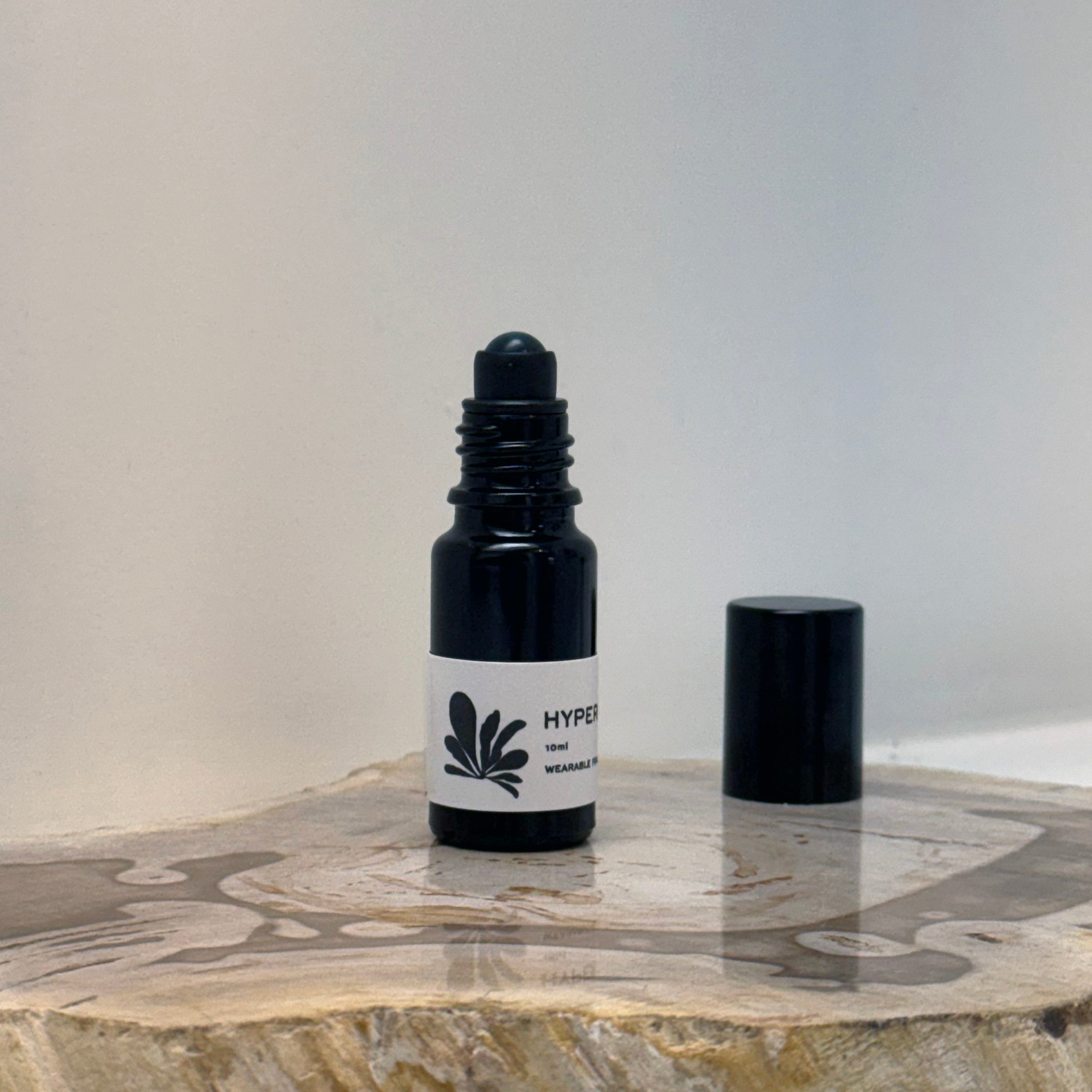 Black roller bottle with a white label on a marble surface